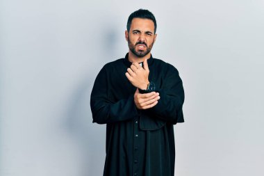 Sakallı, Katolik rahip cüppeli, elleri ve parmakları ağrıyan yakışıklı İspanyol bir adam. Eklem iltihabı. 