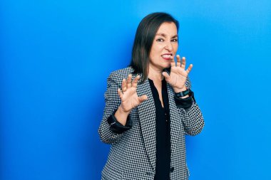 Orta yaşlı İspanyol kadın iş kıyafetleri giyiyordu. İfadeleri iğrençti ve tiksinti ifadesi takınıyordu. Tiksinti reaksiyonu yüzünden iğreniyordu. Eller havada. 