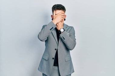 Kulakları genişlemiş, iş ceketi giymiş ağzı ve gözlerini kapayan, şaşırmış ve şok olmuş beyaz bir çocuk. duygu gizleme 