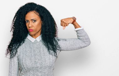 Orta yaşlı Afro-Amerikan kadın günlük kıyafetler giyiyor güçlü kol kası gösteren, kendinden emin ve güçle gurur duyan biri. 
