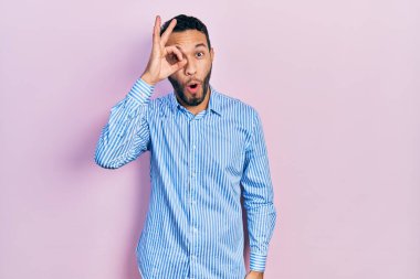 Sakallı, sıradan mavi tişörtlü İspanyol bir adam. Şaşırmış yüz ifadesiyle şaşırmış, parmaklarından bakan bir jest yapıyor. İnançsız ifade. 