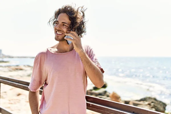 Ung Latinamerikansk Man Ler Glad Talar Smartphone Stående Stranden — Stockfoto