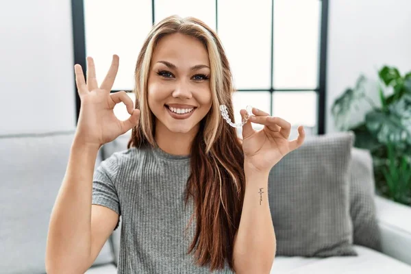 Młoda Kaukaska Kobieta Trzyma Niewidzialny Wyrównawczy Ortodontyczny Robi Znak Palcami — Zdjęcie stockowe