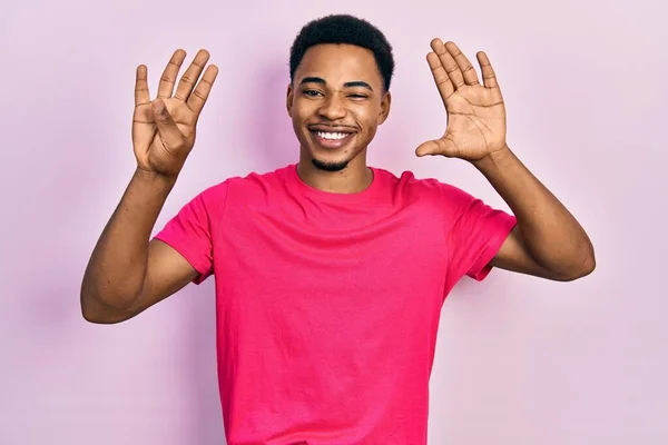 自信と幸せ笑顔ながら若いアフリカ系アメリカ人男性を着てカウアキャストシャツを表示し 指番号9で指摘します — ストック写真