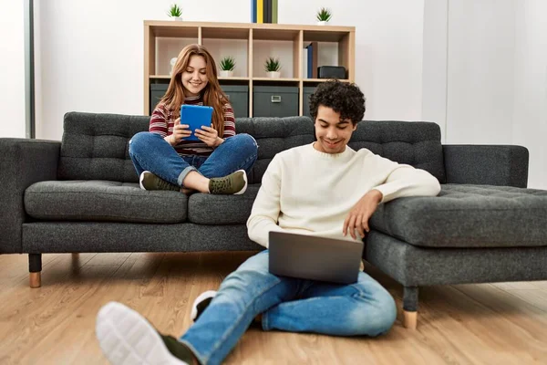 一对年轻夫妇坐在沙发上 一边笑一边用笔记本电脑和触摸板开心地笑着 — 图库照片