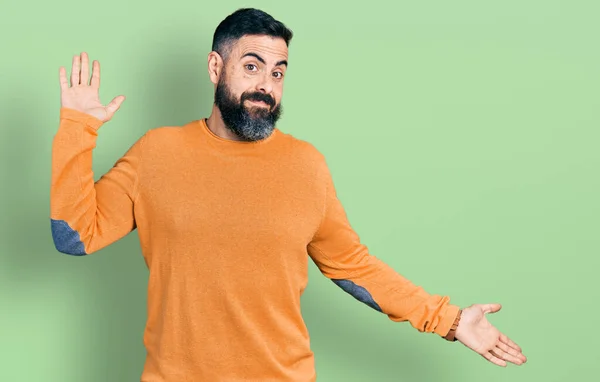 カジュアルな冬のセーターを着て髭を生やしたヒスパニック系の男性は 腕や手を上げて混乱した表情 疑わしい概念 — ストック写真