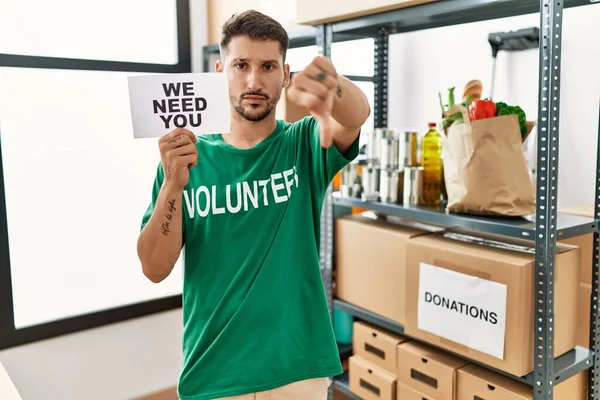 Joven Hombre Hispano Con Camiseta Voluntaria Sosteniendo Necesitamos Bandera Con — Foto de Stock