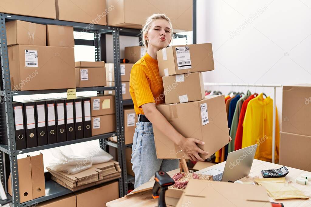 Young blonde woman working at small business ecommerce looking at the camera blowing a kiss being lovely and sexy. love expression. 