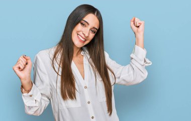 Genç, güzel bir kadın, gündelik beyaz gömlekler giyip dans ediyor, mutlu ve neşeli, gülümsüyor, rahat ve kendinden emin bir şekilde müzik dinliyor. 