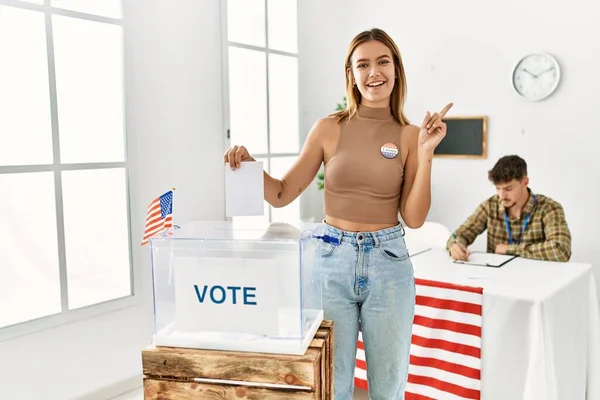 若いですブロンド女の子投票入れEnvelopeで投票箱笑顔幸せなPointingとともに手と指へザ側 — ストック写真
