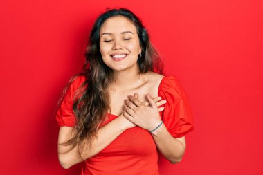 Gündelik kıyafetler giyen genç İspanyol kız elleri göğsünde, gözleri kapalı ve yüzünde minnet dolu bir jest ile gülümsüyor. sağlık kavramı. 