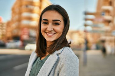 Genç İspanyol kız gülümseyerek şehirde mutlu mesut dikiliyor..