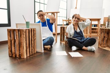 Sanat stüdyosundaki genç İspanyol çift elleri havada, şaşırmış ve sinirli yüzleriyle stresli ve hayal kırıklığına uğramış. 