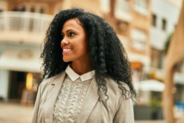 Orta yaşlı Afro-Amerikan iş kadını şehirde mutlu bir şekilde dikilirken gülümsüyor.