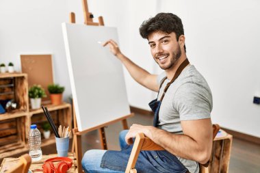 Resim stüdyosunda gülümseyen genç İspanyol ressam..