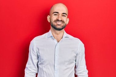 Yüzünde mutlu ve havalı bir gülümseme olan zarif kıyafetler giyen genç kel bir adam. şanslı kişi. 