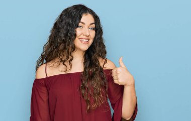 Gündelik kıyafetler giyen genç İspanyol kız elleriyle mutlu bir jest yapıyor. Kameraya bakıp başarıyı gösteren ifade. 