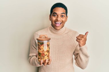 Genç, yakışıklı, elinde makarna kavanozu olan, ağzı açık gülümseyen bir İspanyol. 