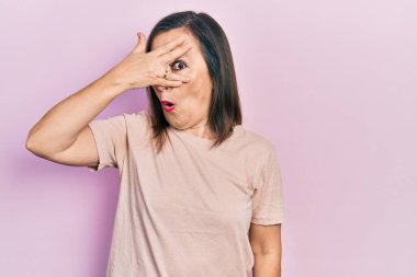 Orta yaşlı İspanyol kadın gündelik giysiler giymiş. Şoka girmiş. Yüzü ve gözlerini kapamış, utanmış ifadesiyle parmaklarından bakıyor.. 