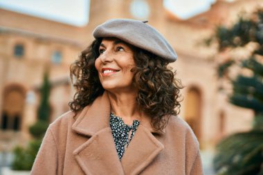 Orta yaşlı İspanyol kadın gülümseyerek şehirde mutlu mesut dikiliyor..