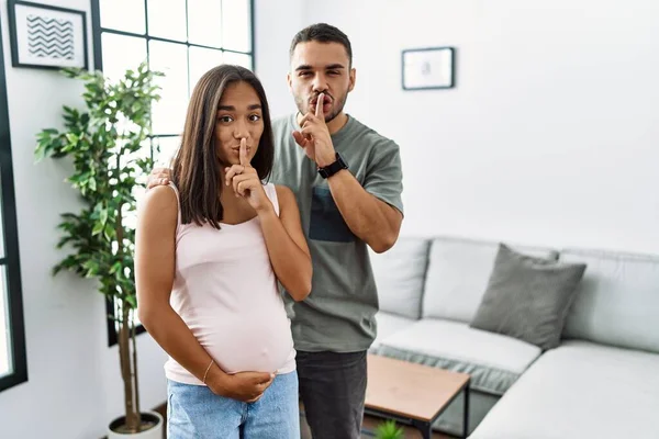 若い異人種間のカップルの赤ちゃんを期待し 唇に指で静かにするように求めて妊娠中の腹に触れる 沈黙と秘密の概念 — ストック写真
