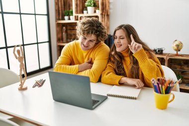 Genç beyaz çift evde online resim dersi aldıklarından emin gülümsüyor.