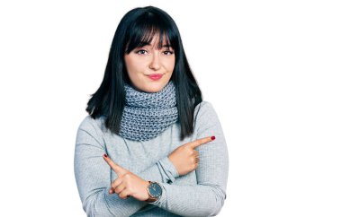 Latin kökenli, uzun boylu, kış eşarbı takan iki tarafı da parmaklarıyla gösteren genç bir kadın. Farklı yönlerden. 