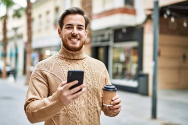 Kafkasyalı genç adam akıllı telefon kullanıyor. Şehirde kahve içiyor..