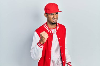 Beyzbol üniforması giyen genç Afro-Amerikan bir adam öfkeyle bağırırken kızgın ve kızgın yumruk kaldırıyor. öfke ve agresif konsept. 