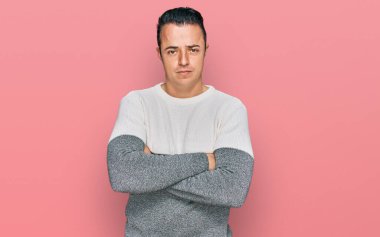 Kış süveteri giyen yakışıklı genç adam kuşkucu ve gergin, suratında çapraz kollu tasvip etmeyen ifade. negatif kişi. 