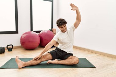 Genç İspanyol adam gülümsüyor spor merkezinde esniyor.