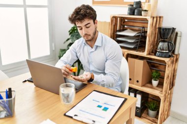 Ciddi bir ifadeyle genç İspanyol işadamı ofiste hap alıyor..