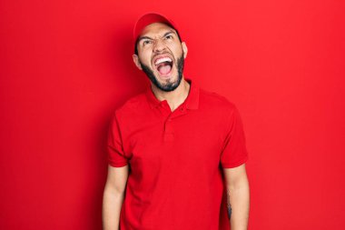 Sakallı, teslimat üniformalı, şapkalı öfkeli ve sinirli bağıran öfkeli bir İspanyol. Öfkeyle bağırıyor. öfke ve agresif konsept. 