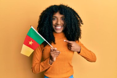 African american woman with afro hair holding senegal flag smiling happy pointing with hand and finger  clipart