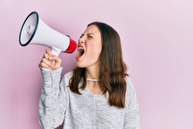 Genç esmer kadın pembe izole arka planda megafonla bağırıyor ve çığlık atıyordu.
