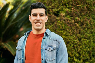 Genç İspanyol adam gülümseyerek şehirde mutlu mesut dikiliyor..