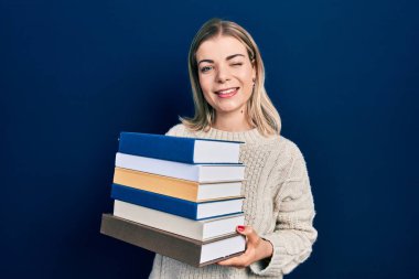 Güzel beyaz kadın elinde kitap yığınıyla kameraya bakıyor. Seksi bir ifadeyle, neşeli ve mutlu bir yüzle.. 