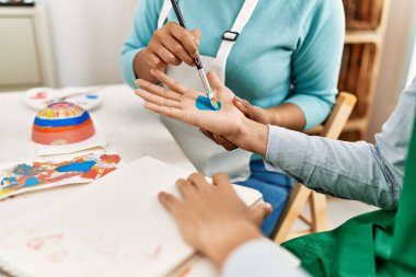 Genç Latin ressam çift gülümsüyor resim stüdyosunun masasında mutlu bir resim çiziyor.