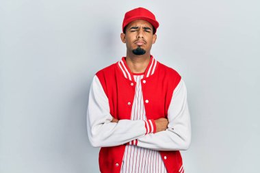 Beyzbol üniforması giyen, kuşkucu ve gergin genç bir Afro-Amerikan erkeği. Yüzünde çapraz kollarla onaylamayan bir ifade var. negatif kişi. 