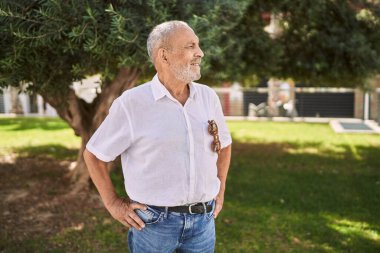 Kıdemli adam parkta kendinden emin gülümsüyor.