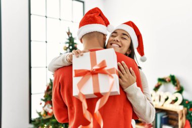 Genç Latin çift mutlu bir şekilde gülümsüyor ve evde Noel hediyesi tutuyorlar..
