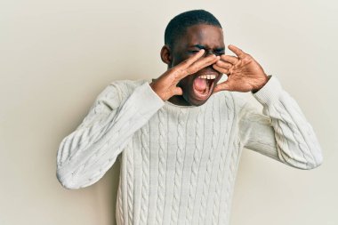 Gündelik kıyafetler giyen genç Afro-Amerikan adam elleri ağızda bağırarak bağırıyor. 