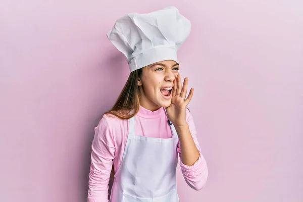 美丽的黑发小女孩穿着专业厨师的围裙和帽子 大喊大叫 一边手拉手 传播概念 — 图库照片
