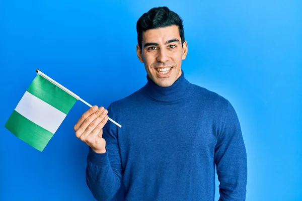 Hombre Hispano Guapo Sosteniendo Bandera Nigeria Mirando Positiva Feliz Pie —  Fotos de Stock