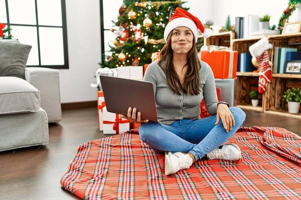 Молодая Латиноамериканка Сидящая Ноутбуке Рождественской Ёлкой Пыхтя Щеками Забавным Лицом — стоковое фото