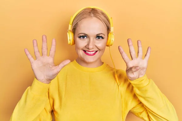 Młoda Blondynka Słuchająca Muzyki Pomocą Słuchawek Pokazujących Wskazujących Palcami Numer — Zdjęcie stockowe