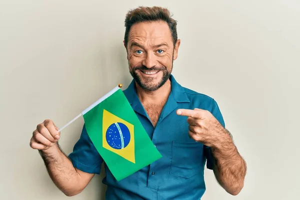 Muž Středního Věku Drží Brazilskou Vlajku Úsměvem Ukazující Rukou Prstem — Stock fotografie