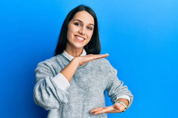 大小のサインを示す手でジェスチャーカジュアル服を着て若いヒスパニック系の女性は シンボルを測定します カメラを見て笑ってる 概念を測定し — ストック写真