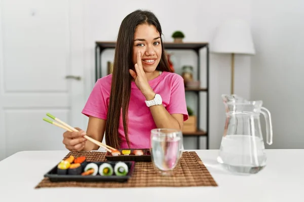 年轻的黑发女人在吃寿司时 用筷子捂着嘴说着秘密的谣言 窃窃私语着恶毒的谈话 — 图库照片