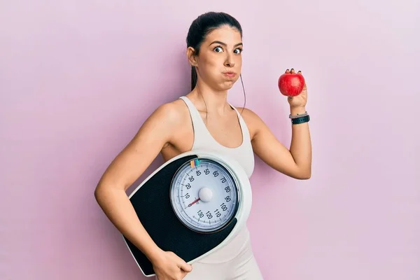 Junge Hispanische Frau Sportkleidung Mit Wiegemaschine Und Apfelbäckchen Mit Lustigem — Stockfoto